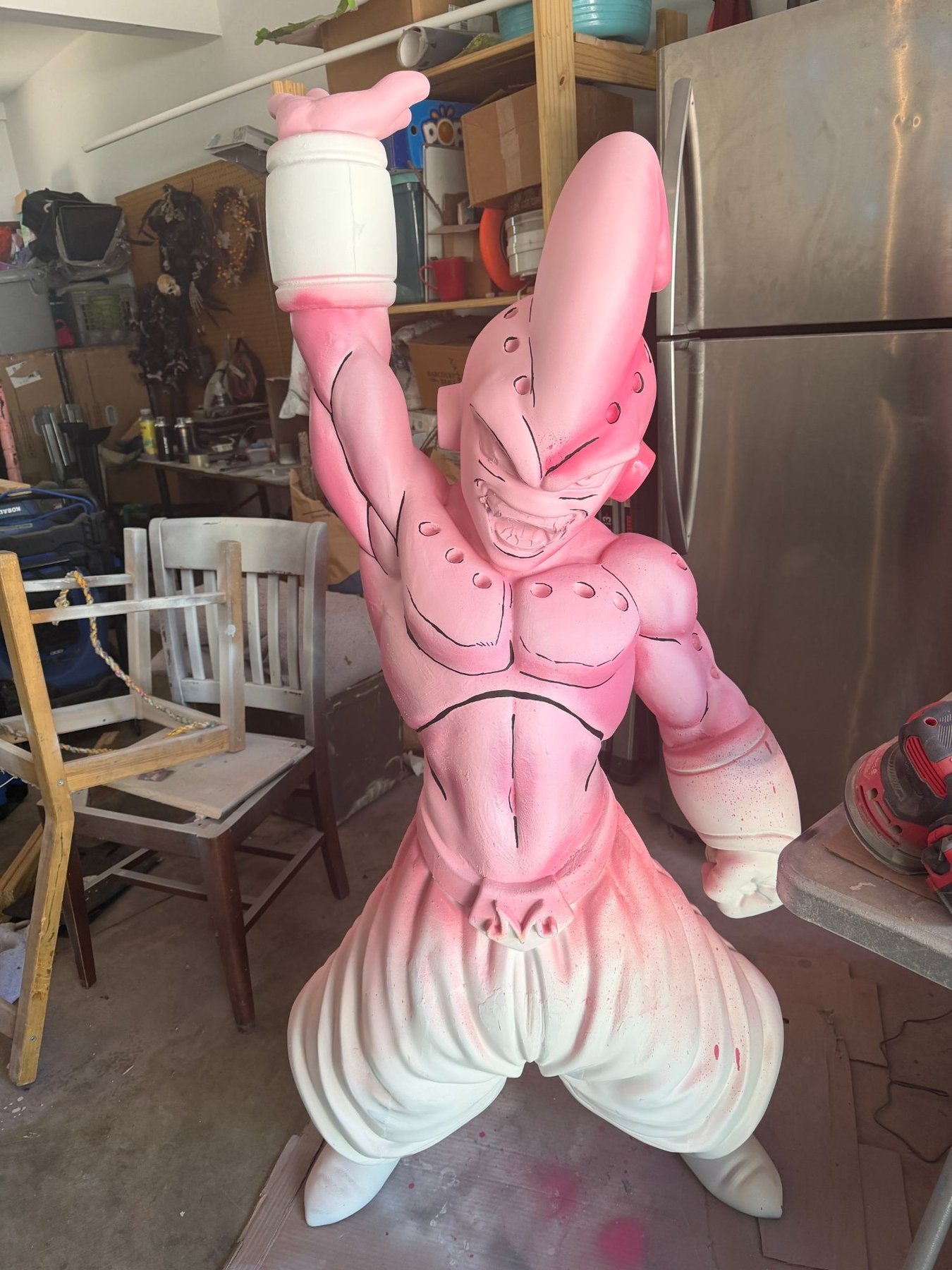 A large 3D-printed Majin Buu figure, airbrushed pink and white, standing in a garage workshop.